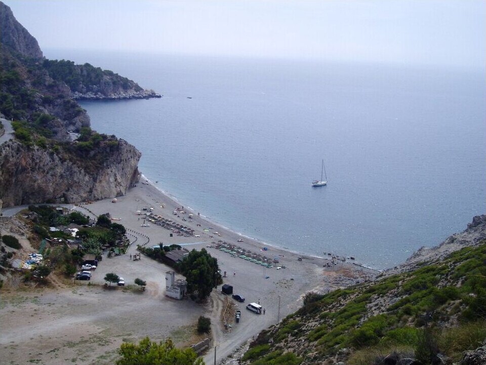 Cantarriján beach below steep green and rocky slopes